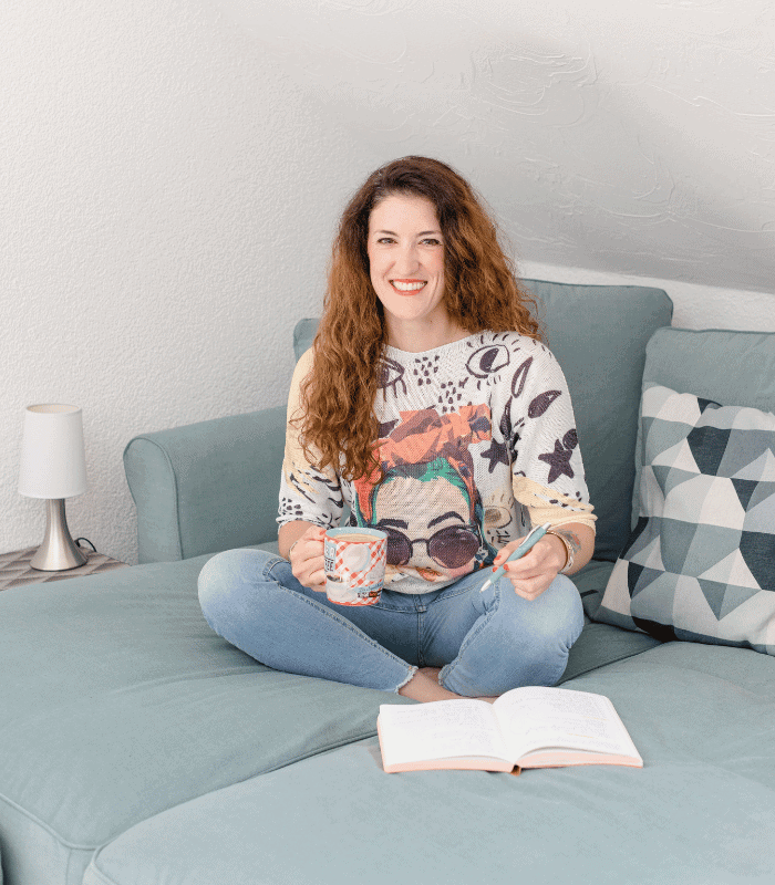 Jessica sitzt mit Journal und Kaffe auf ihrer Couch